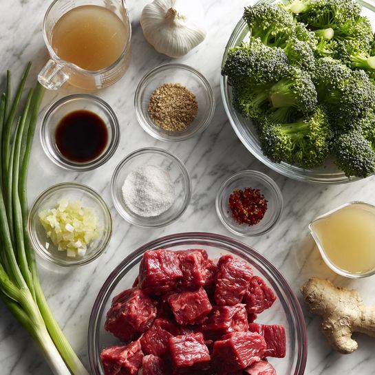 The image shows fresh cooking ingredients neatly arranged on a white marbled surface. In the center, a clear glass bowl holds bright red raw beef pieces with a slightly marbled texture. To the right and above it, another clear glass bowl is filled with vibrant green broccoli florets, their bumpy texture clearly visible. Surrounding these bowls are small clear glass bowls and containers with various ingredients: light brown brown sugar, black soy sauce, white sesame seeds, minced garlic, and red chili flakes. A larger clear glass measuring cup contains a light brown sauce, while a small glass bowl holds pale yellow minced ginger. Fresh ginger root sits near the bowls, and a bunch of long, slender green spring onions is placed to the left. A whole bulb of white garlic is also visible near the top. The setup looks clean and fresh, ready for meal preparation. photo taken with an iphone --ar 4:5 --v 7