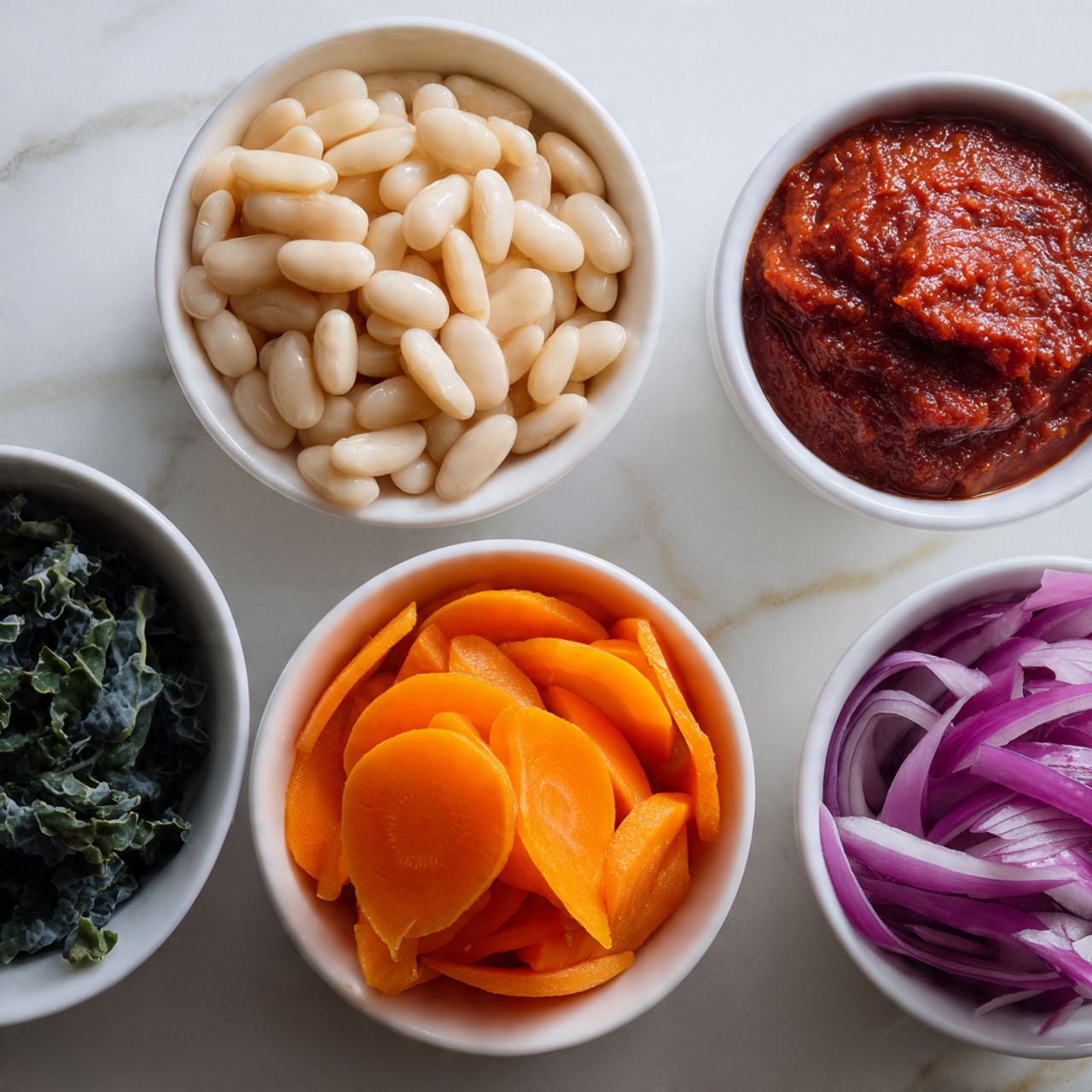 The image shows five small white bowls on a white marbled surface. One bowl is filled with white beans that have a smooth texture, another with bright orange carrot slices in flat, round shapes. There is a bowl containing dark green leaves that look slightly curly and textured, another with thin slices of light purple onion with smooth, shiny layers, and a small bowl holding a thick red paste or sauce with a slightly rough texture in the center top of the image. Photo taken with an iphone --ar 4:5 --v 7