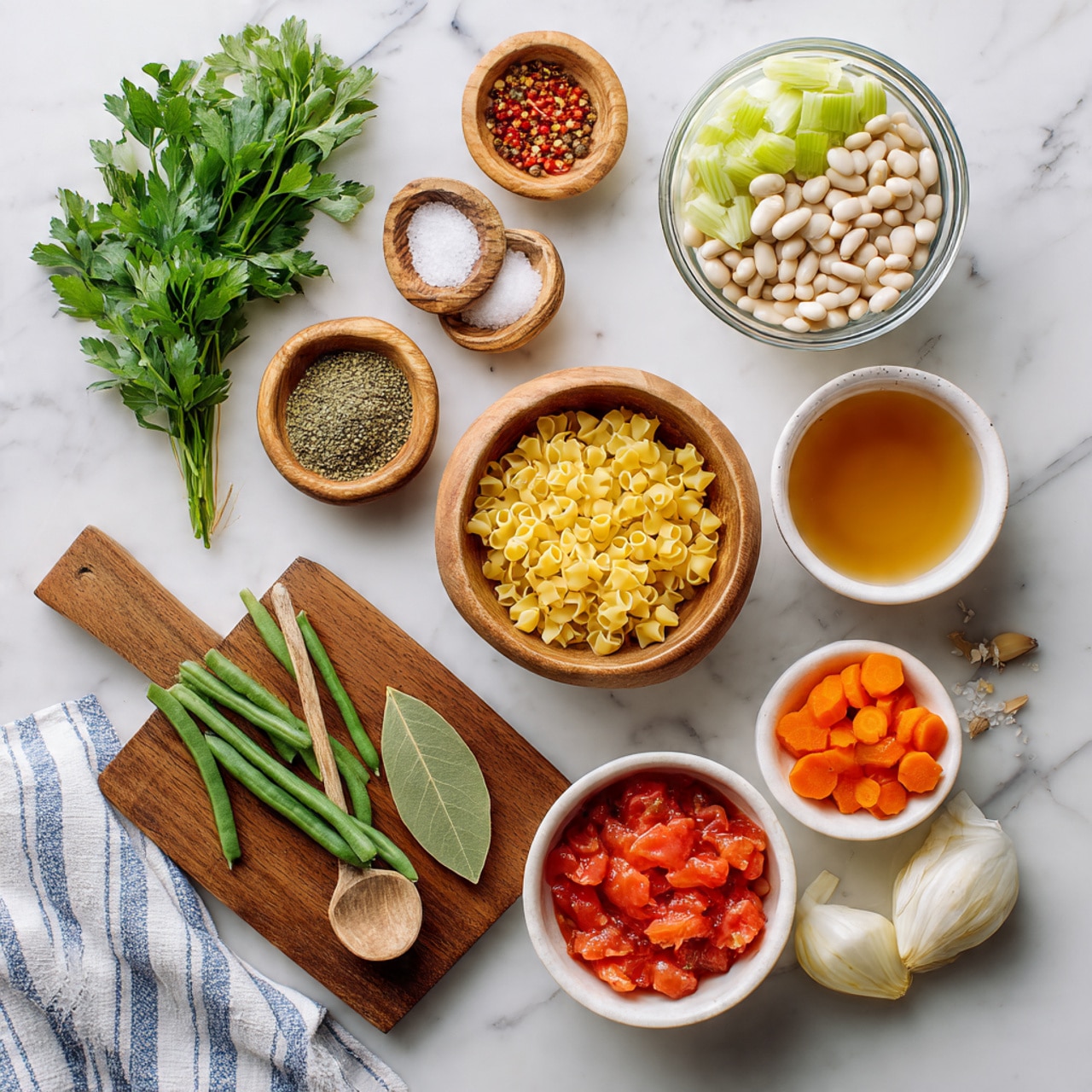 A top-down view of various fresh ingredients neatly arranged on a white marbled surface, starting with a bunch of green parsley leaves at the top left, followed by small wooden bowls of salt, red pepper flakes, and dried herbs. Next to these is a clear glass bowl filled with white beans, and another bowl with light green celery slices. Below, a wooden bowl holds small yellow pasta pieces with a wooden spoon resting inside. To the right, a white bowl contains bright orange round carrot slices, and in front of it, another white bowl holds chunky red diced tomatoes in juice. On a wooden board below these are two bay leaves, fresh green beans, a whole pale yellow onion, and a few peeled garlic cloves. A small glass bowl of light brown broth is placed at the top right. A striped white and blue kitchen towel is partially visible beneath the bowls. Photo taken with an iphone --ar 4:5 --v 7