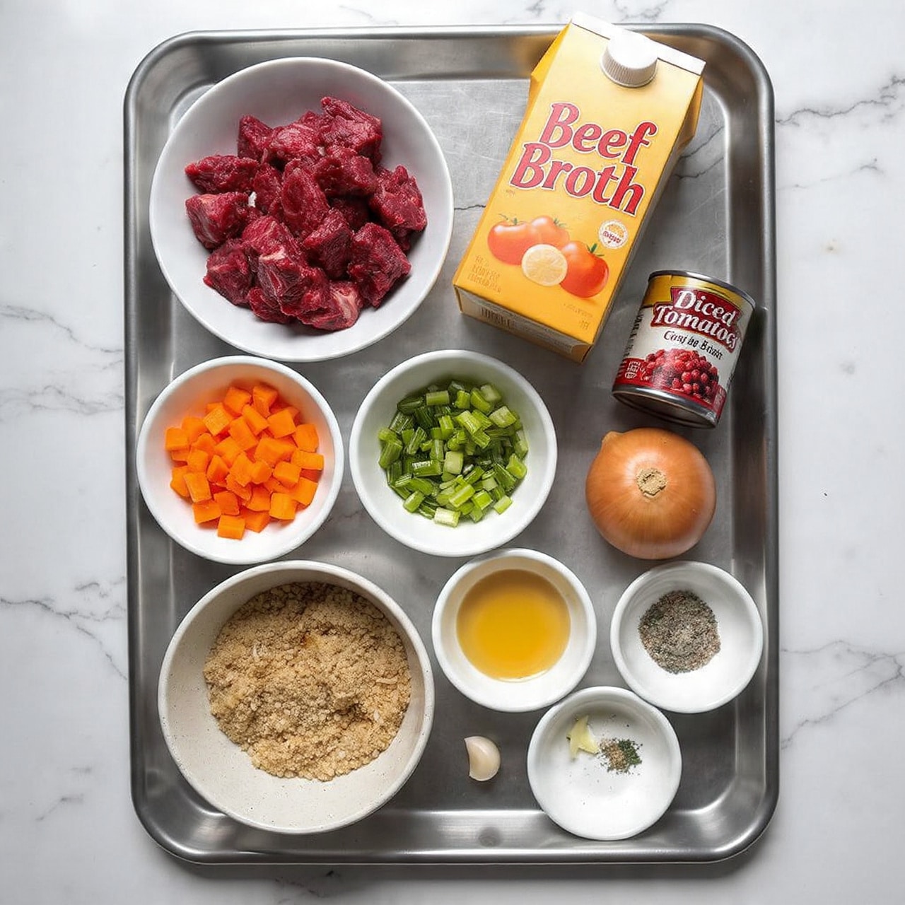 The image shows a metal tray on a white marbled texture surface with several small white bowls and containers arranged neatly on it. The top left bowl holds raw dark red beef chunks, while the top right has a light yellow-orange carton labeled