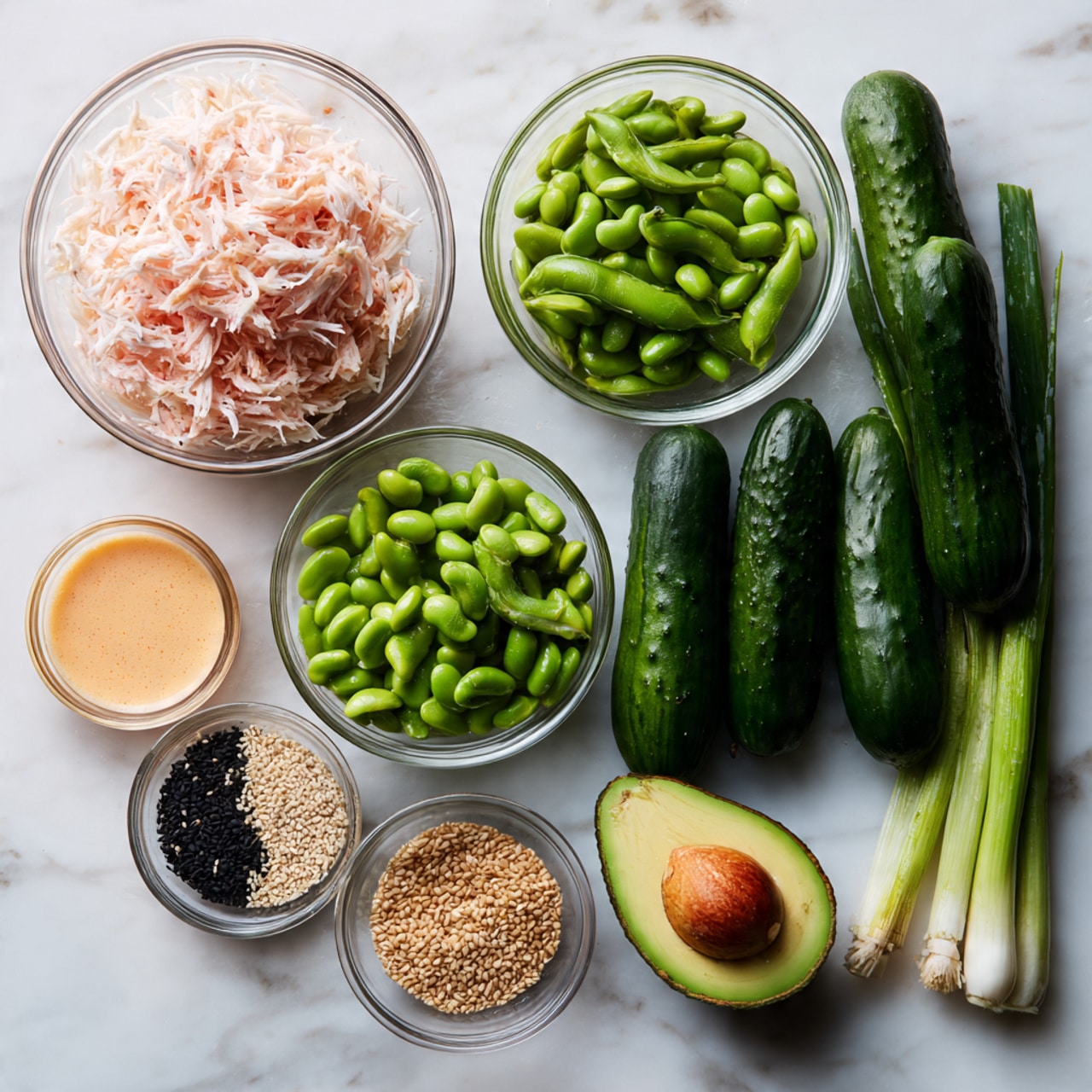 The image shows six fresh dark green cucumbers stacked in the middle of a white marbled surface. To the top left, there is a clear bowl filled with white and pink shredded crab meat. Below that, there is another clear bowl holding bright green edamame beans. In the middle bottom, a small clear bowl contains a mix of white and black sesame seeds. To the left of the cucumbers, there is a clear bowl with light orange creamy sauce. On the right side, there are two halves of a green avocado with a seed in one half and the empty inside visible in the other. At the bottom right corner, there are several long green onions with white bulbs placed side by side photo taken with an iphone --ar 4:5 --v 7