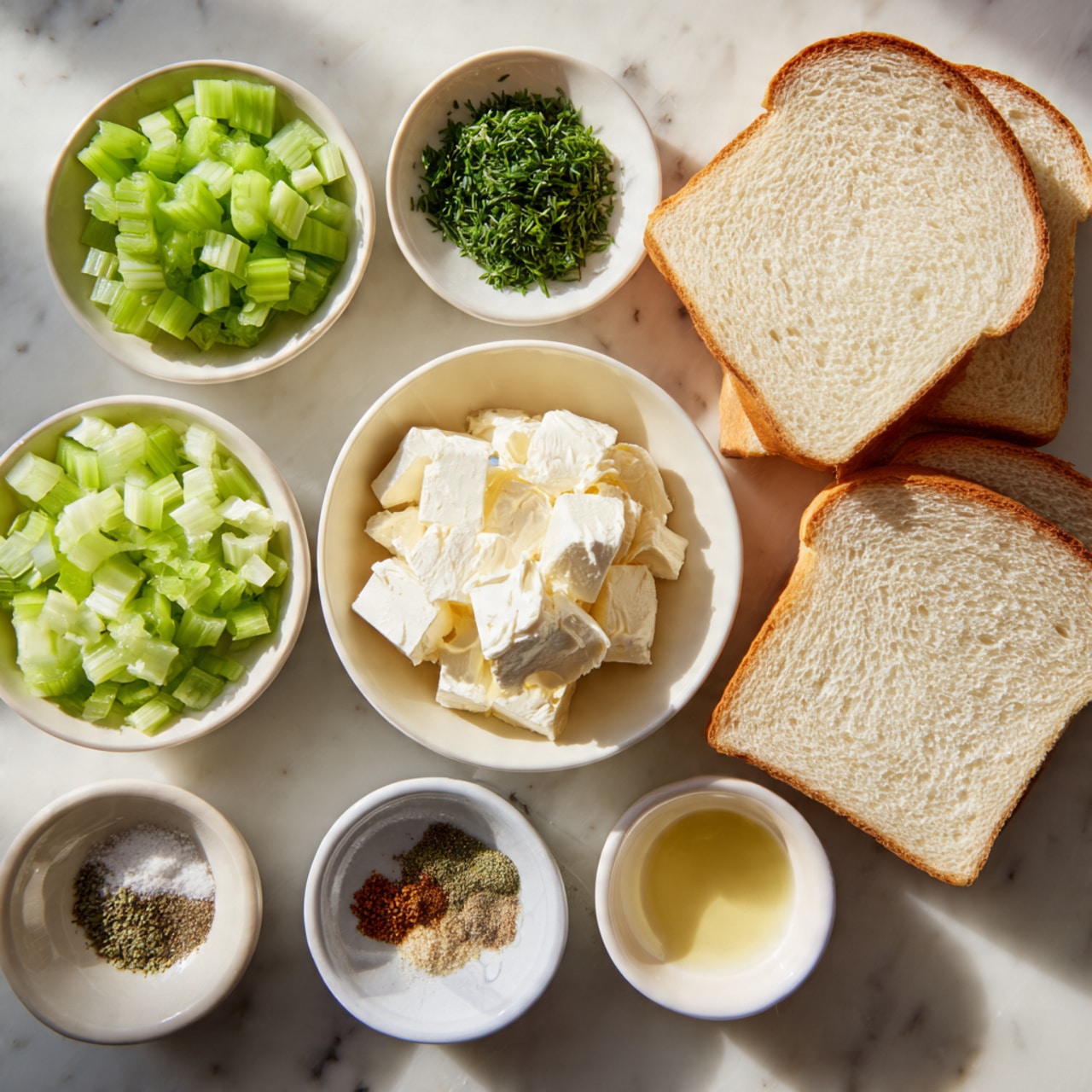 The image shows a white marbled surface with ingredients neatly arranged. There are four slices of plain white bread in the top right corner. Surrounding them are small white bowls holding green diced celery, a mound of white cream cheese, a dollop of pale yellow mayonnaise, finely chopped green herbs, melted butter, and seasoning powders like salt, pepper, and a light-colored spice. Everything is spaced evenly and clearly visible, ready for making a sandwich. photo taken with an iphone --ar 4:5 --v 7