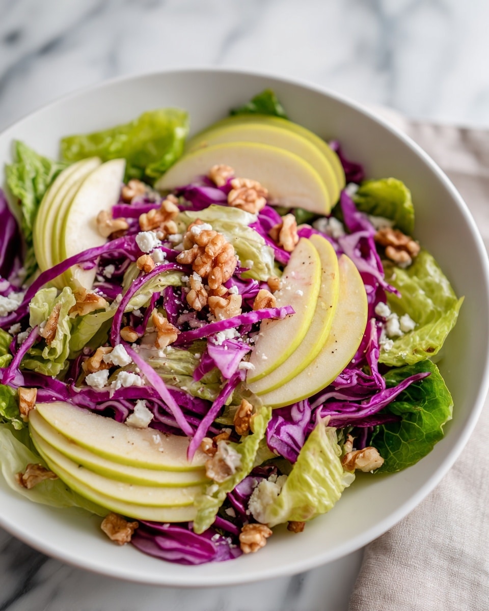The image shows a white bowl filled with a fresh salad. The salad has a base layer of green lettuce leaves, topped with thin slices of green apple arranged evenly around the bowl. There are also small pieces of walnuts scattered on top, adding a rough texture. Thin strips of purple cabbage are spread across the salad, adding bright color contrast. Some light dressing and small bits of white cheese are sprinkled over everything. The bowl sits on a white marbled surface. Photo taken with an iphone --ar 4:5 --v 7
