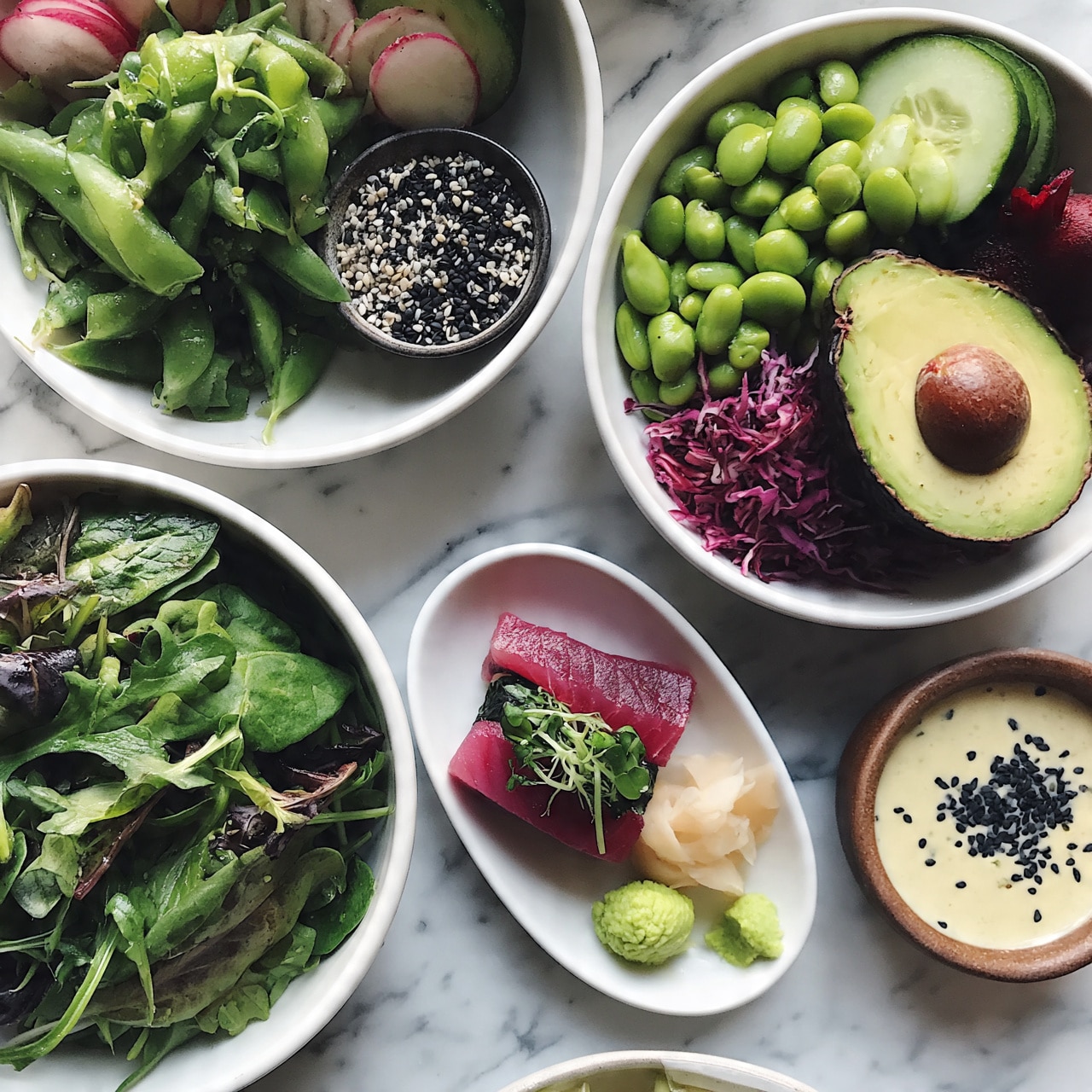 square image The image shows several white bowls and dishes on a white marbled surface. One bowl is filled with mixed green leafy vegetables including spinach, arugula, and snap peas, giving it a fresh and vibrant green texture. Another bowl contains bright green edamame beans, sliced cucumbers, radish slices, shredded purple cabbage, a halved avocado with its pit, and a small red beet, creating a colorful and layered mix of textures and colors. A small white dish holds a thick slice of deep pink raw tuna rolled up with green microgreens and small piles of light cream-colored pickled ginger and bright green wasabi. A small dark bowl is filled with a mixture of black and white sesame seeds. Lastly, a brown bowl contains a creamy light yellow sauce topped with black sesame seeds. Photo taken with an iphone --ar 4:5 --v 7
