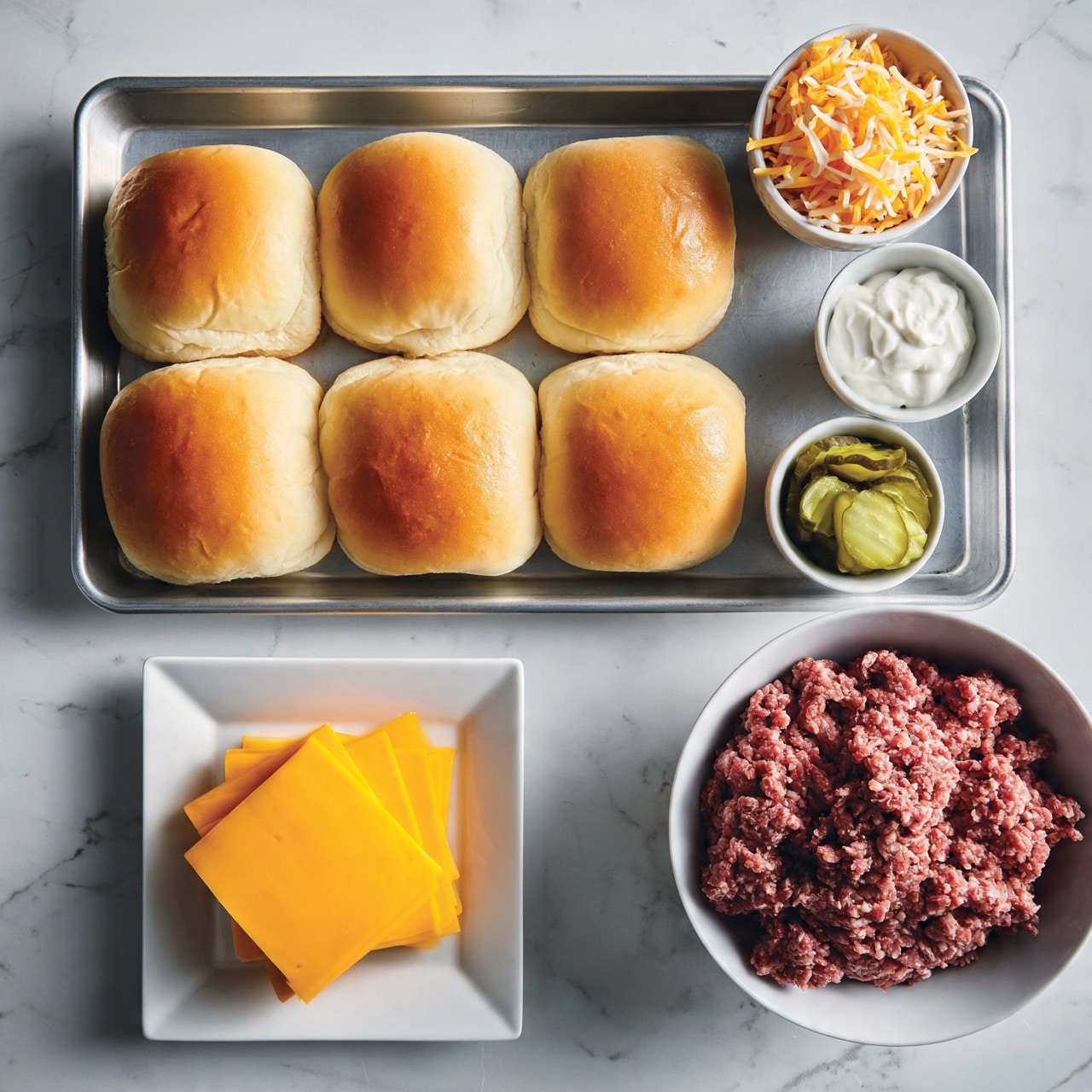 square image The image shows a metal tray with six soft, golden-brown hamburger buns arranged neatly in two rows of three. To the right of the tray are three small white bowls: the top bowl is full of shredded orange and white cheese, the middle bowl holds white creamy dressing, and the bottom bowl contains sliced green pickles. Below the tray, there is a white square plate with four slices of bright yellow cheese stacked on each other. A larger white bowl with raw ground meat sits next to the cheese plate. All items are placed on a white marbled surface. Photo taken with an iphone --ar 4:5 --v 7