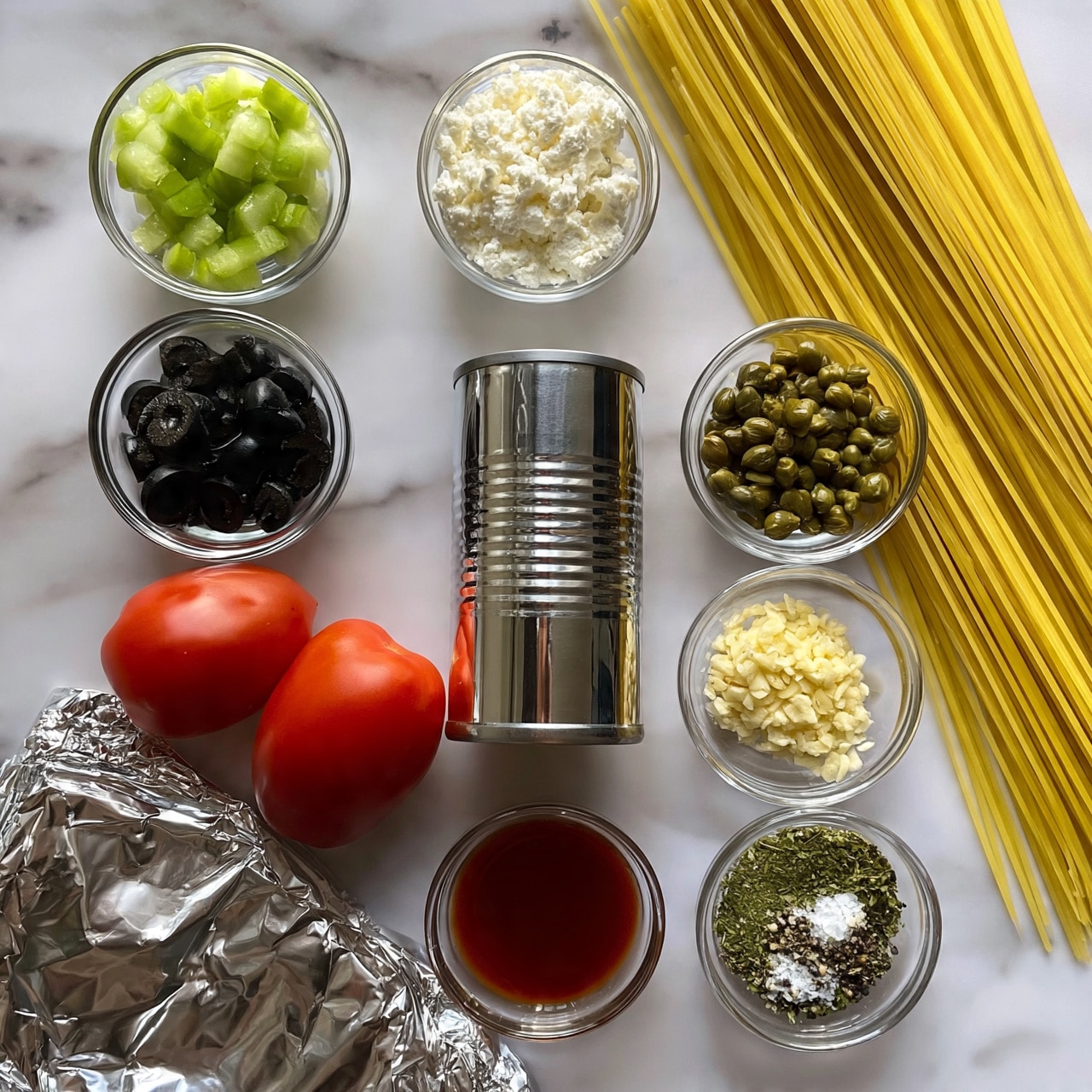 square image A flat lay image of various cooking ingredients arranged neatly on a white marbled surface, including a shiny silver canned item near the center, long dry yellow spaghetti pasta on the right side, and small glass bowls filled with chopped green cucumber, white crumbled cheese, black sliced olives, green capers, minced garlic, dried green herbs with salt and pepper, and a red liquid. Two red Roma tomatoes lie near the middle left, along with a silver foil package on the bottom left. The image has good lighting and clear focus. photo taken with an iphone --ar 4:5 --v 7