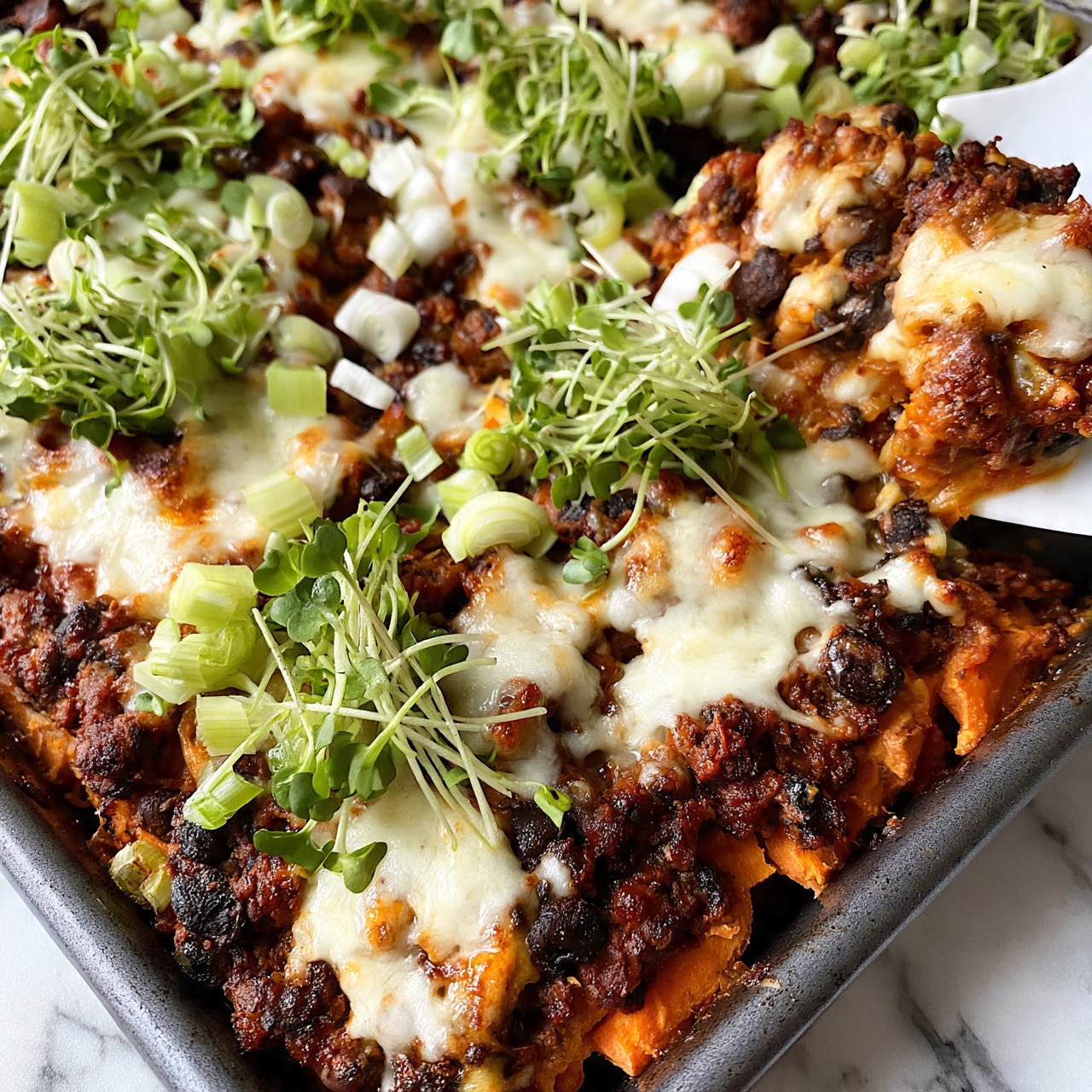 square image The image shows four baked sweet potatoes, each sliced open and filled with layers of ingredients. The first layer is the soft orange sweet potato flesh, topped with green leafy vegetables and small green broccoli stalks. Scattered on top are roasted golden-brown chickpeas mixed with dark dried cranberries. A light creamy white sauce is drizzled over the fillings, adding a smooth texture. The potatoes are arranged on a white plate with some chickpeas scattered around. In the top right corner, there is a white bowl filled with a creamy light-colored sauce, garnished with a slice of lemon. All of this sits on a white marbled surface. Photo taken with an iphone --ar 4:5 --v 7