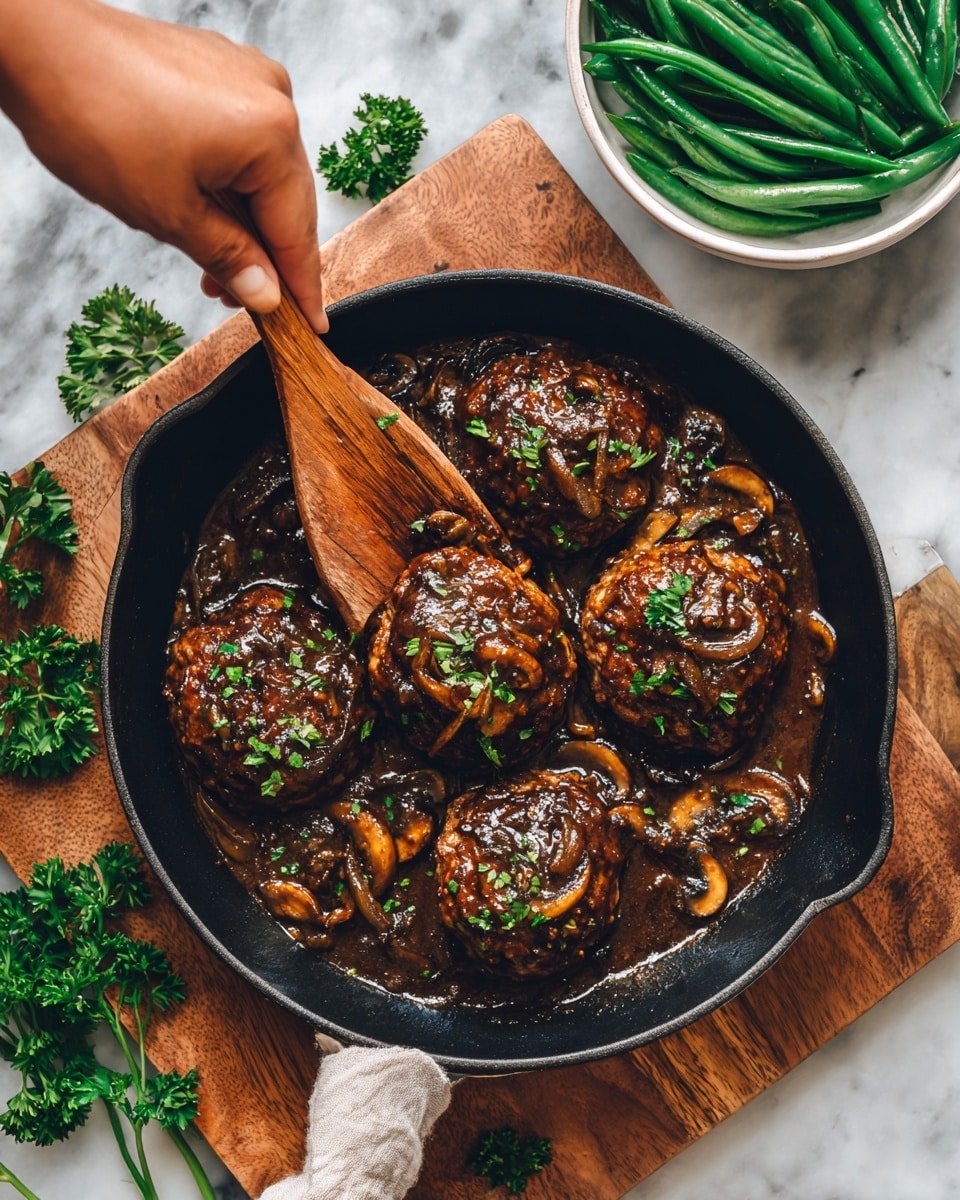 A black cast iron pan filled with five browned hamburger patties covered in a thick, dark brown mushroom and onion gravy, with small green herb pieces sprinkled on top. A wooden spatula, held by a woman's hand, lifts one patty above the pan, showing the shiny, saucy texture and the cooked mushrooms and onions on the surface. The pan rests on a wooden board, with fresh parsley leaves scattered around it. In the background, there is a white bowl filled with green beans and a white marbled textured surface as the backdrop. photo taken with an iphone --ar 4:5 --v 7
