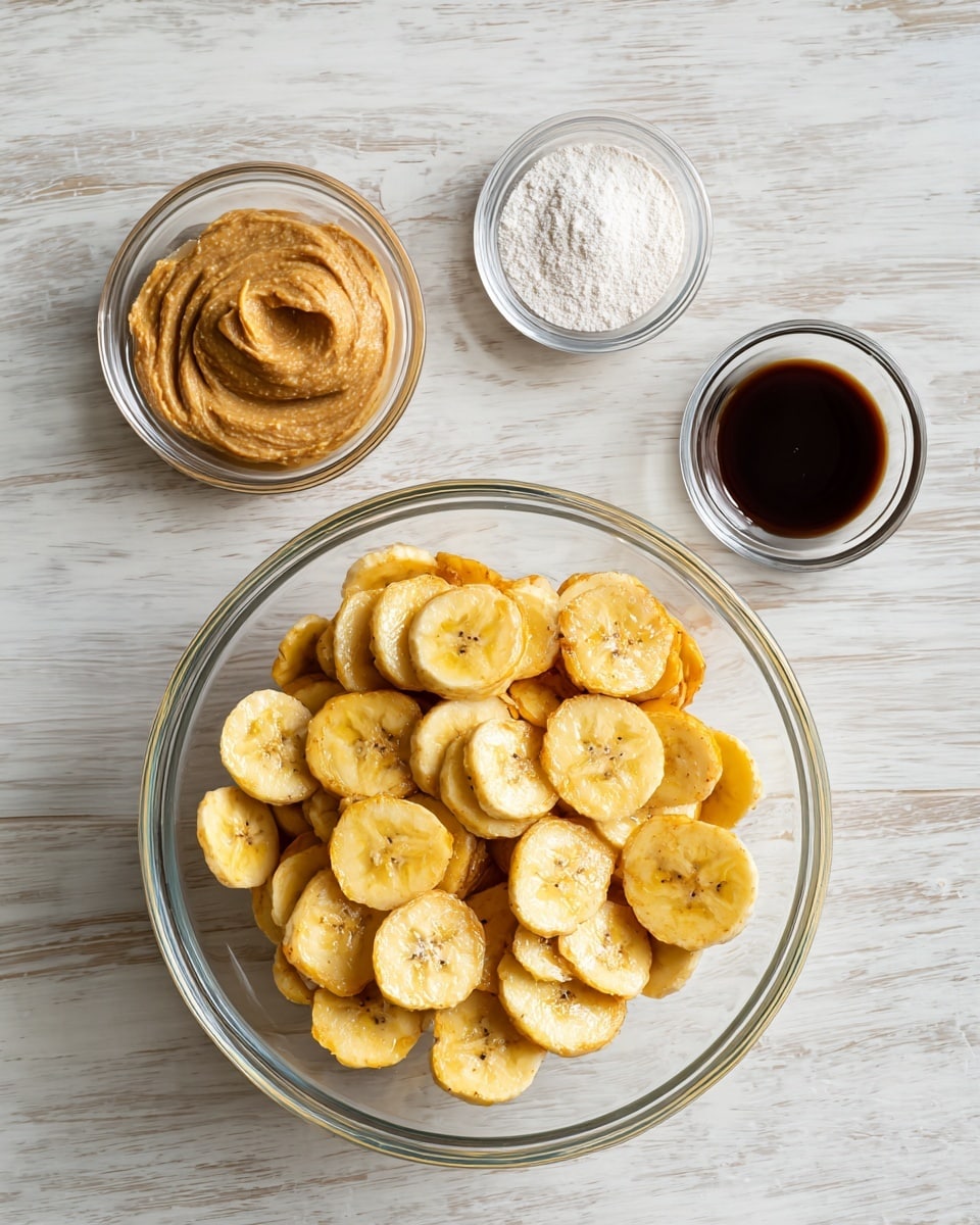 A clear glass bowl filled with whole banana chips sits on a light wood surface. Surrounding it are three smaller clear glass bowls: one with a thick light brown paste, one with a dark liquid, and one with a white powdery substance. The arrangement is simple and clean, with the bowls spaced evenly, all placed on a white marbled texture. Photo taken with an iphone --ar 4:5 --v 7