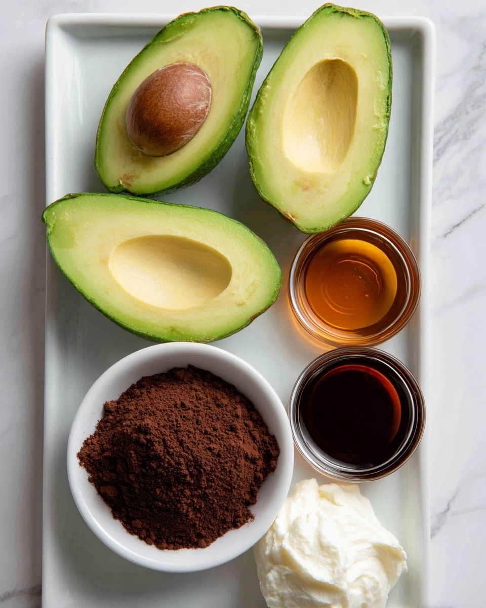 The image shows a white rectangular tray on a white marbled surface holding five ingredients. In the top left, a halved avocado with its seed is next to another half with the pit cavity visible, both bright green with a smooth texture. Below the avocado, there is a white bowl filled with dark brown cocoa powder, fluffy and fine. To the right of the bowl, two small round glass containers hold dark brown and amber liquids, glossy and clear. On the upper right corner of the tray, there is a small blob of white, creamy substance with a smooth texture. Each item is neatly placed with some space between them. Photo taken with an iphone --ar 4:5 --v 7