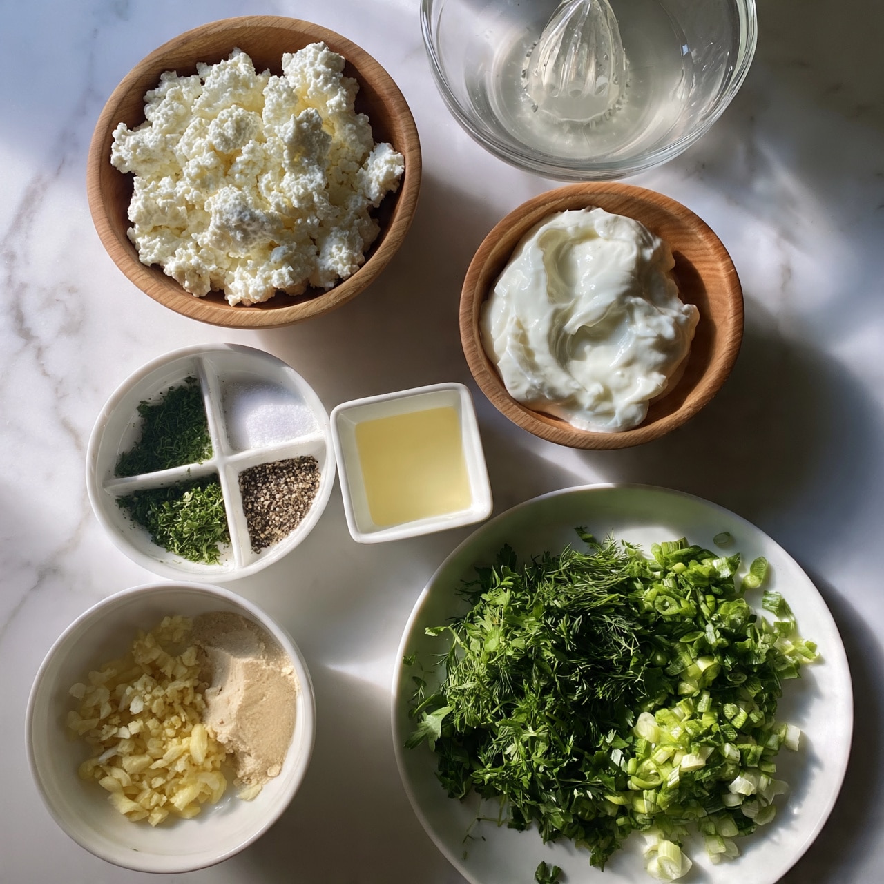 square image The image shows several white bowls and a white plate placed on a white marbled surface, each filled with different cooking ingredients. Starting from the top left, there is a wooden bowl filled with thick, white cottage cheese textured with small lumps. To the right, a clear glass bowl holds a transparent liquid with a pressed citrus juicer inside. Below that, a wooden bowl contains smooth, white sour cream with a soft, creamy texture. Below the cottage cheese, a white bowl is divided into sections with green dried herbs on one side and salt and ground pepper on the other. Next to it, a small white square bowl holds a light yellow liquid resembling lemon juice. At the bottom left, a white bowl contains minced garlic, minced ginger, and a light beige powder, likely a spice. Finally, a white plate displays chopped fresh green herbs and vegetables like dill, parsley, and chopped green onions in bright shades of green. The overall setting is neat and clean, with fresh and natural ingredients arranged carefully. photo taken with an iphone --ar 4:5 --v 7