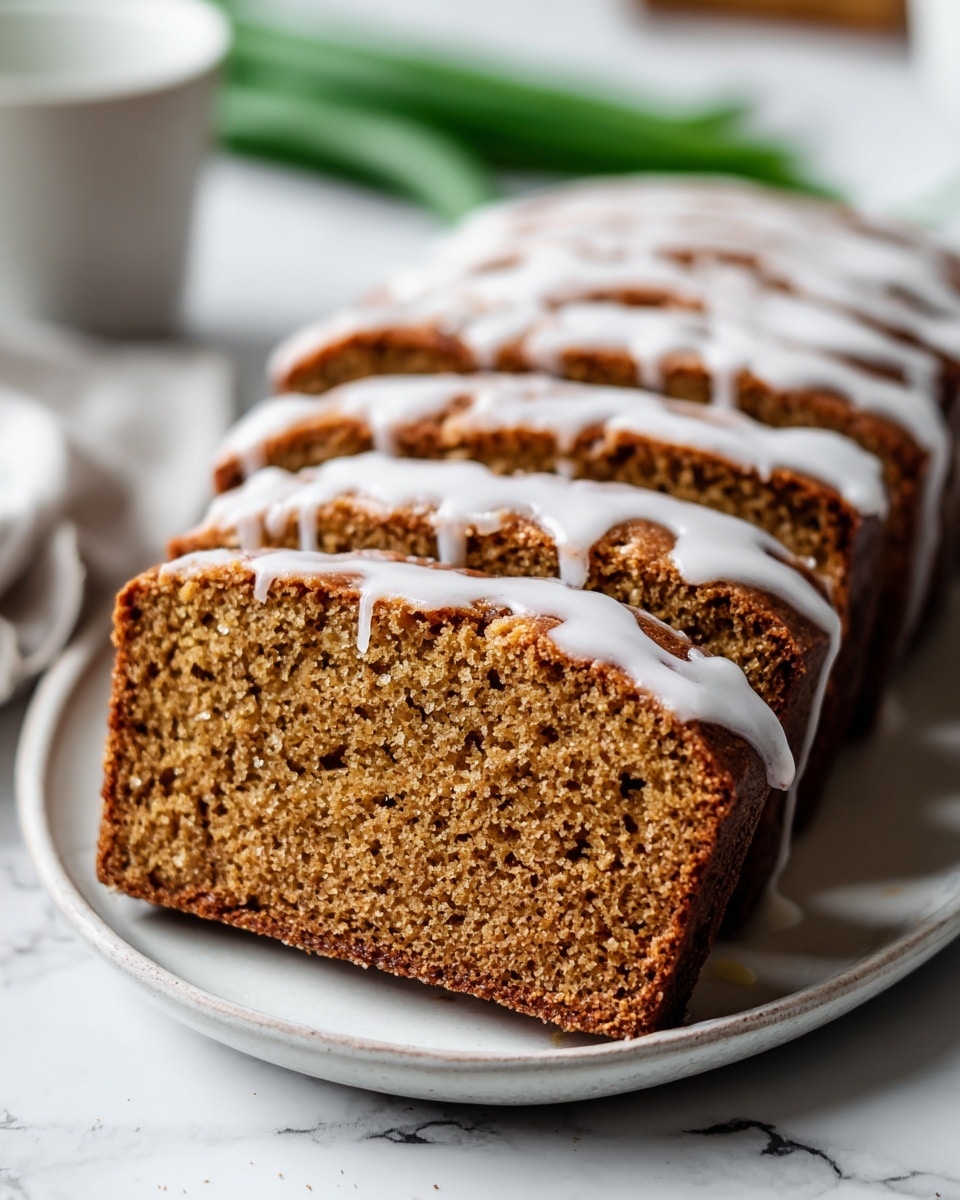 The image shows multiple slices of a brown loaf cake lined up on a white plate, each slice showing a moist and slightly crumbly texture with small flecks inside, indicating ingredients mixed in the batter. The top layer of the cake is covered with a light, creamy glaze that drips down the sides unevenly, adding a shiny and smooth contrast to the rough cake surface. The background is softly blurred green, highlighting the cake slices in the foreground. The scene is set on a white marbled surface. Photo taken with an iphone --ar 4:5 --v 7