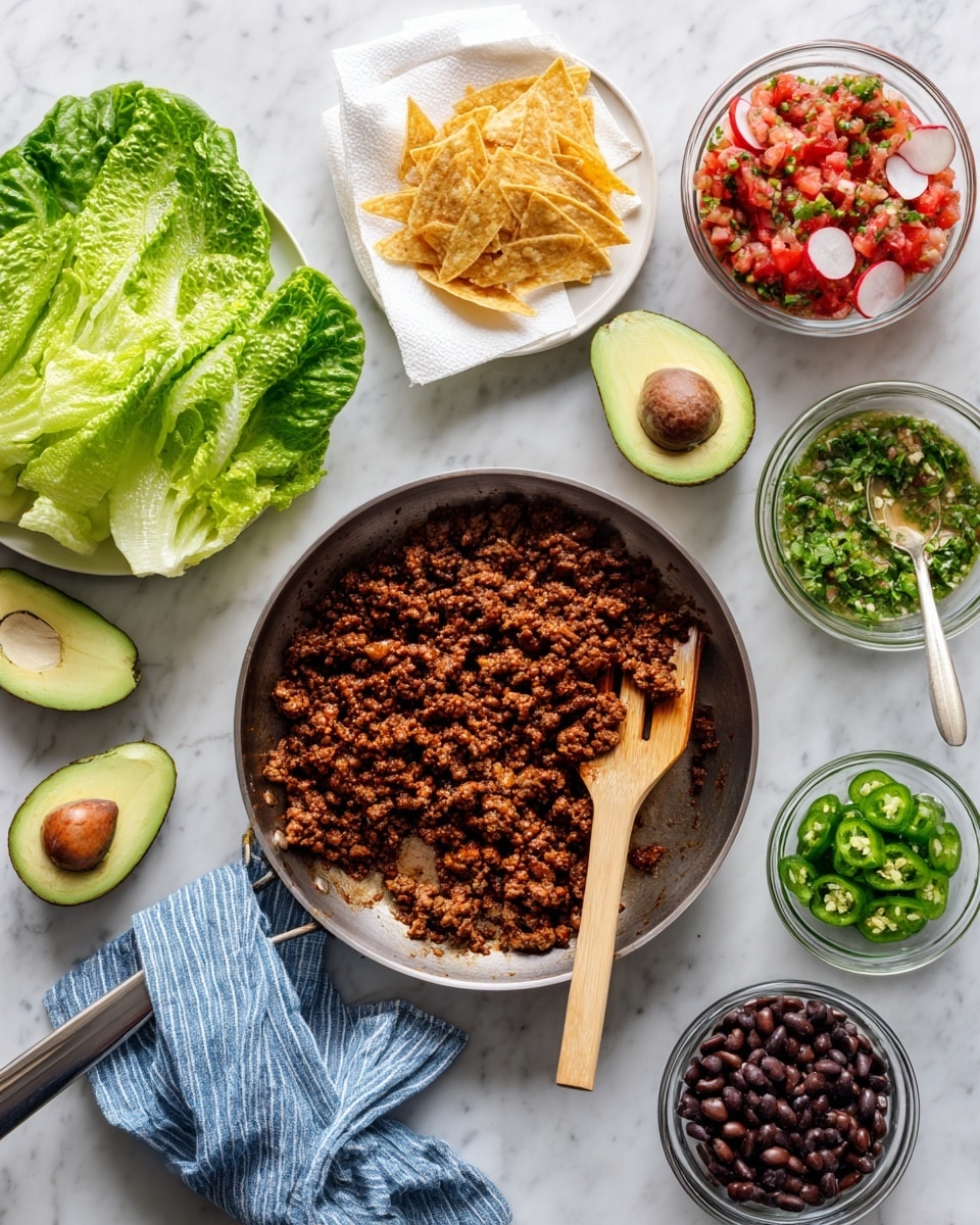 A cooking pan with brown cooked ground meat sits in the center on a white marbled surface, a wooden spatula resting inside. To the left, several green romaine lettuce leaves lie flat with a bowl of thin white radish slices nearby. Above the lettuce, a halved avocado with a visible seed rests. Above the pan, on a white plate lined with white paper, there are golden fried tortilla strips. To the right of the pan, there are three small clear glass bowls holding fresh red and white salsa, green sliced jalapenos, and green sauce respectively. In the bottom left corner, there is a bowl of mixed black and brown beans. The pan handle is covered with a blue and white striped cloth. photo taken with an iphone --ar 4:5 --v 7