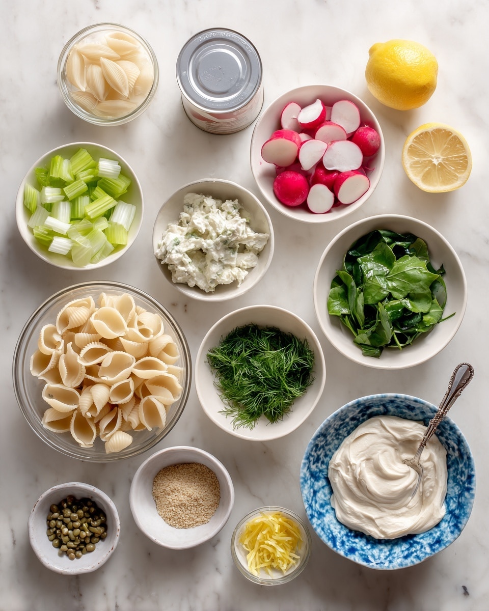 The image shows a white marbled surface with several white bowls and one clear bowl filled with various ingredients arranged neatly. In the front left corner, there is a clear bowl with uncooked shell pasta, and next to it, a small closed can with a white lid. Above are chopped green celery pieces in a white bowl. Nearby, a bowl holds sliced radishes with red edges and white inside. Another white bowl is filled with bright green chopped spinach, while the bowl beside it contains finely chopped fresh dill and parsley. There is a bowl with small green capers, and another with a creamy white substance, likely cottage cheese. A blue-patterned white bowl is filled with a thick white yogurt or similar ingredient. Near the top center, two lemon halves are placed side by side. A small bowl with bright yellow lemon zest sits near the center, and another holds grainy mustard with a spoon inside. The entire setup is organized on a clean, white marbled surface, photo taken with an iphone --ar 4:5 --v 7