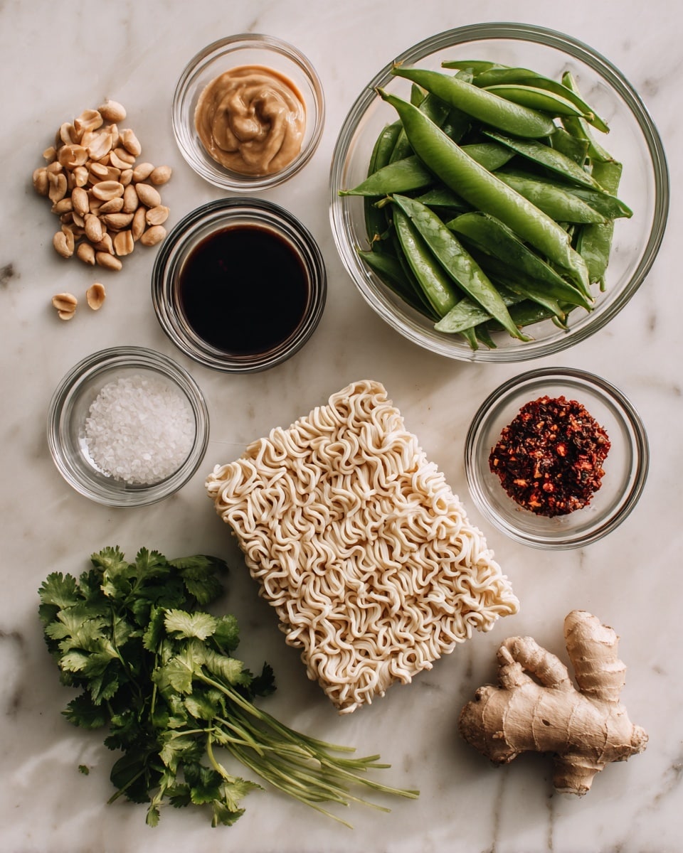 The image shows a white marbled surface with various ingredients arranged neatly. On the right, a clear glass bowl holds fresh green snap peas. Below it, two blocks of uncooked ramen noodles rest side by side, light brown in color with a textured wavy shape. Towards the lower center, a small bunch of fresh green cilantro leaves lie flat. To the left, a handful of light brown peanuts is placed next to two small pieces of fresh ginger root with a beige, knobby appearance. Above them, in the middle, there are four small clear bowls: one with a smooth light tan paste (peanut sauce), another with dark soy sauce, a third with a coarse black and red chili mixture, and the last with a small amount of white granulated salt. The setting is clean and bright. Photo taken with an iphone --ar 4:5 --v 7