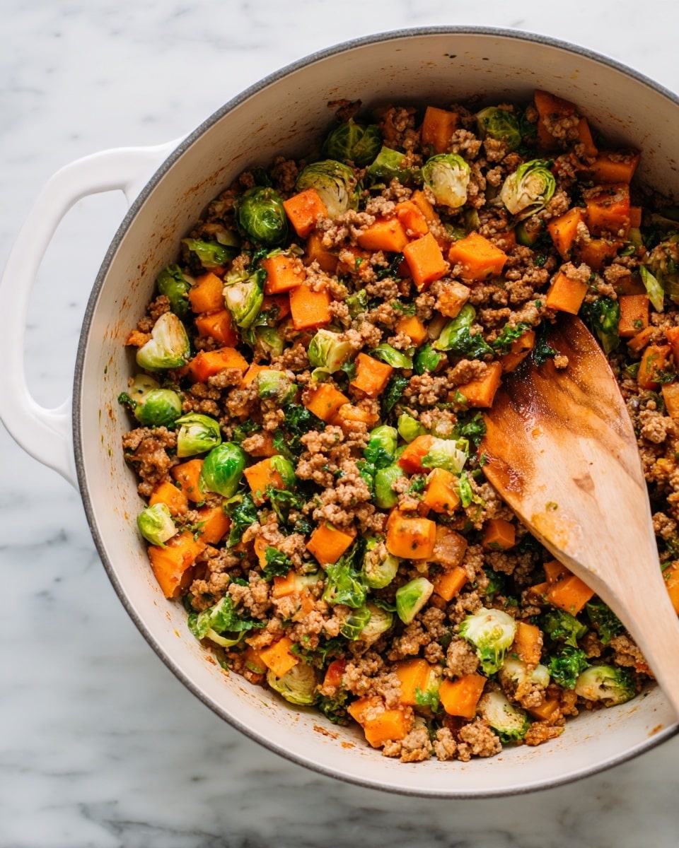 The image shows a close-up of a white pot filled with a colorful cooked mix of ground meat, diced orange sweet potatoes, and bright green Brussels sprout pieces. The ground meat is crumbly and brown, spreading evenly throughout. The cubed sweet potatoes add a soft, orange texture, while the Brussels sprout pieces, some halved, add vibrant green color with a slightly leafy texture. A wooden spoon is placed into the mix on the right side, slightly stained from stirring the ingredients. The dish is set on a white marbled surface. photo taken with an iphone --ar 4:5 --v 7