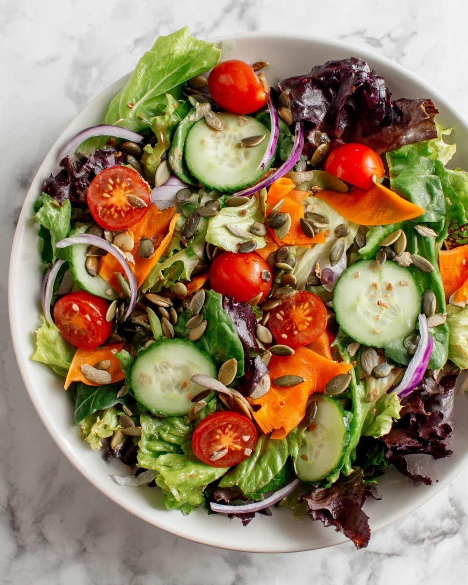 A fresh green salad is shown in a white bowl on a white marbled surface. The salad has several layers: a base of mixed leafy greens with different shades of green and a slightly ruffled texture, slices of light green cucumber scattered on top, bright red cherry tomato halves, thin strips of orange carrot spread evenly, and thin rings of pale purple onion adding color contrast. Small sunflower seeds are sprinkled all over the salad, adding texture. The overall look is vibrant and colorful with a mix of smooth and crunchy textures. Photo taken with an iphone --ar 4:5 --v 7