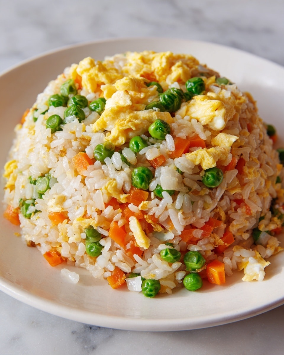 A close-up view of fried rice on a white plate, showing three main layers: the base layer of soft steamed rice in a light beige color, mixed with small cubes of orange carrots and translucent diced onions throughout; the second layer consists of bright green peas spread evenly across the rice; the top layer has small, fluffy scrambled egg pieces in a pale yellow color scattered on top. The rice looks slightly shiny and moist, all set on a white marbled surface. photo taken with an iphone --ar 4:5 --v 7