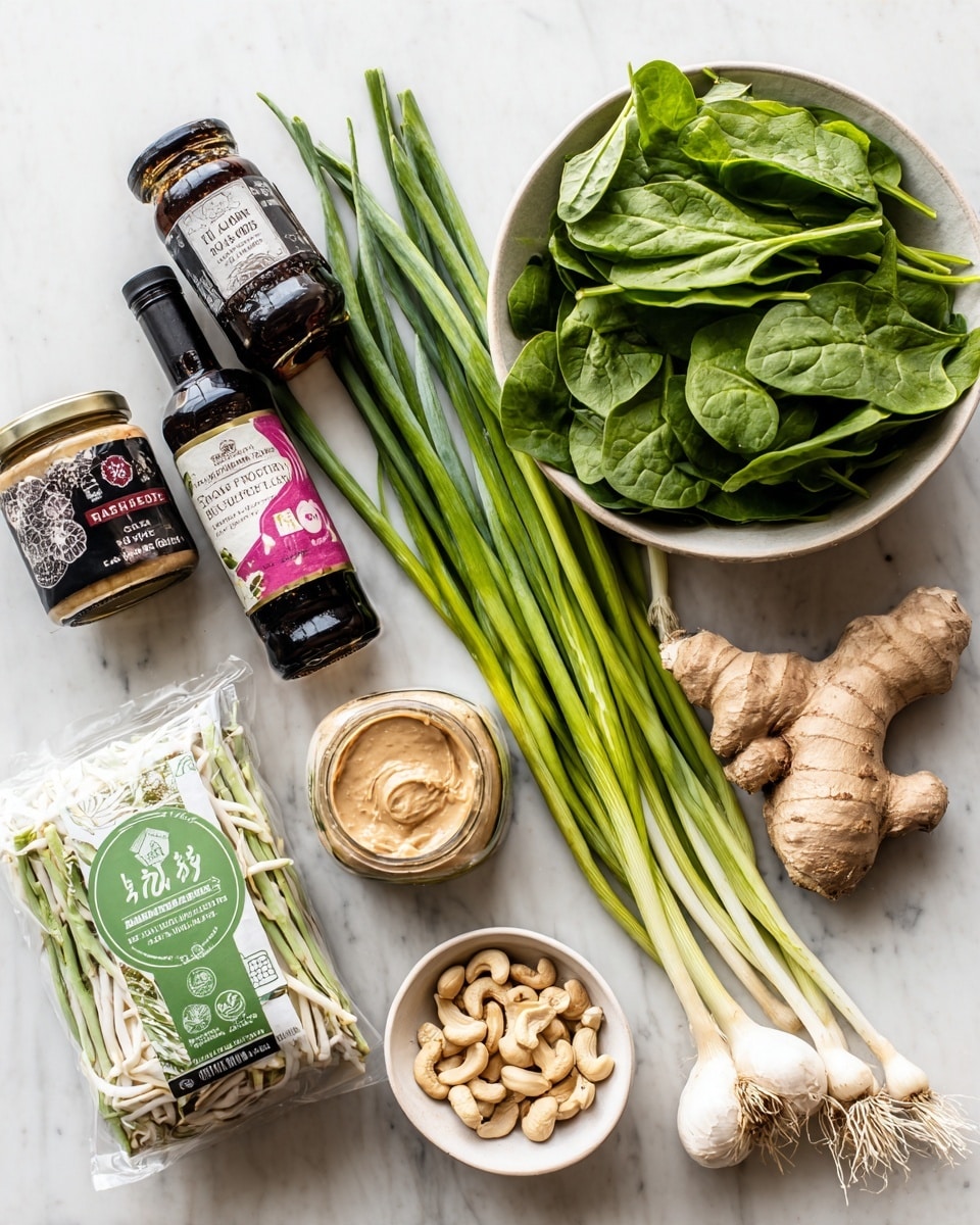 The image shows a set of fresh ingredients neatly arranged on a white marbled surface. There is a white bowl filled with fresh, bright green spinach leaves on the upper right side, next to a bunch of long, fresh green onions laid flat. Just below them, a whole garlic bulb and a thick piece of light brown ginger are placed closely. A small white bowl holding raw cashew nuts is positioned on the left, near a sealed packet of green and white Pad Thai rice noodles. Scattered around are various condiments including a jar of creamy almond butter, a dark glass bottle of tamari soy sauce, a jar of dark hoisin sauce, and a pink and beige tofu package. The items create a well-balanced composition for an Asian-inspired recipe. Photo taken with an iphone --ar 4:5 --v 7