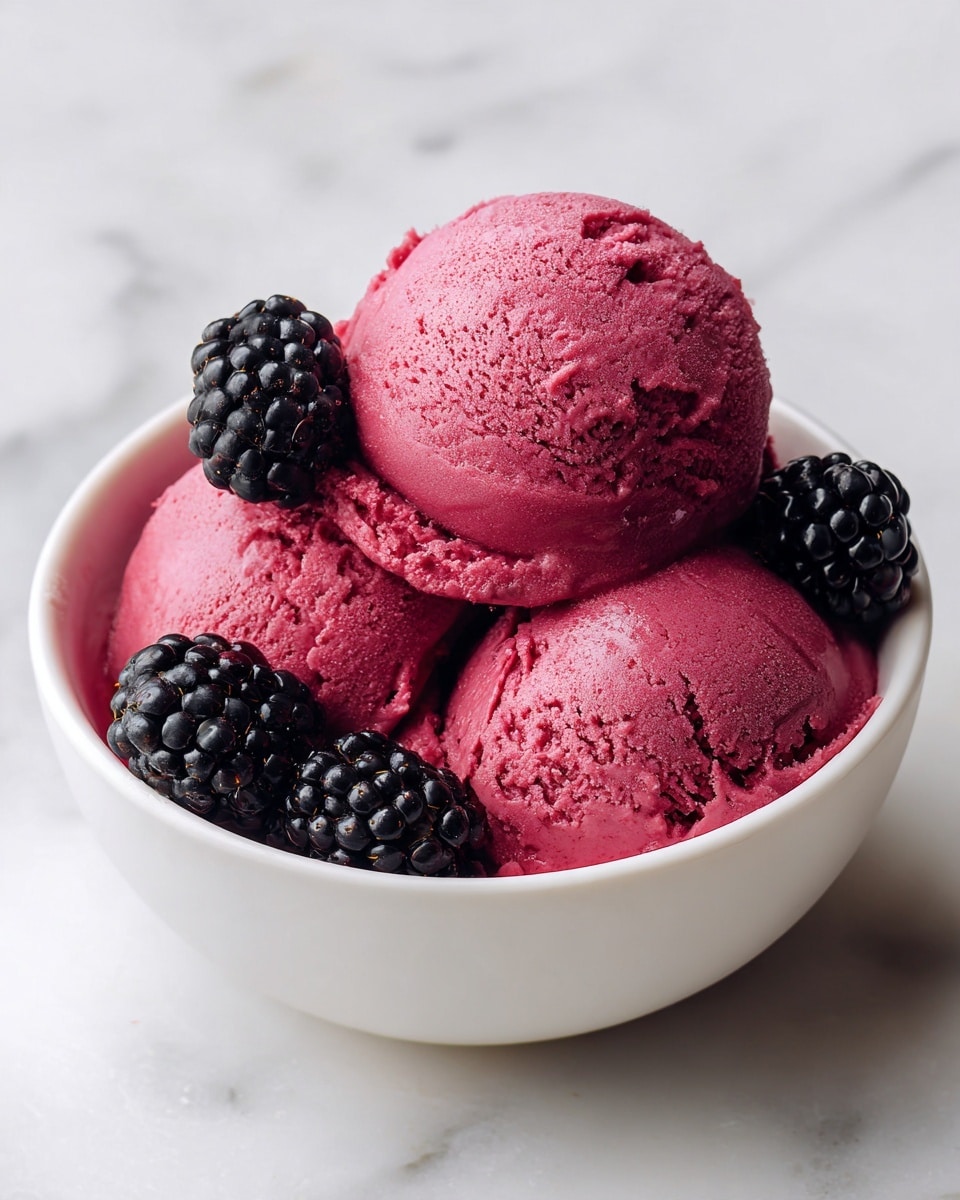 The image shows a white bowl filled with three scoops of dark pink ice cream, each scoop smooth and slightly melting. Around the scoops, there are several blackberries, deep purple-black in color with a shiny and bumpy texture. The bowl sits on a white marbled surface, and the lighting highlights the creamy texture of the ice cream and the freshness of the fruit. photo taken with an iphone --ar 4:5 --v 7
